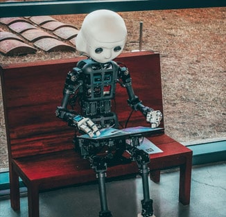 Picture of humanoid robot sitting on a bench reading