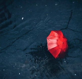 a red umbrella lying on wet, dark pavement